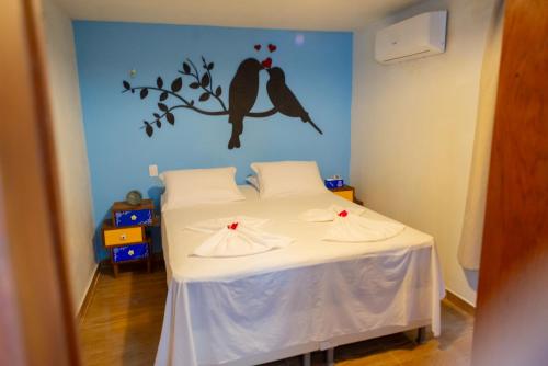 a bedroom with a bed with two birds on the wall at Vila Feliz - Chalés completos - ideal para famílias in Serra de São Bento