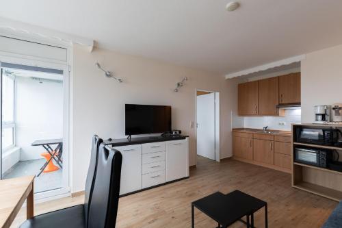 a living room with a large kitchen with a flat screen tv at Haus Frische Brise Sahlenburg Wohnung 12 7 in Sahlenburg