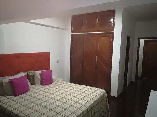 a bedroom with a bed and a cabinet with purple pillows at Oásis Tropical: Flat de Luxo na Beira, Moçambique in Beira