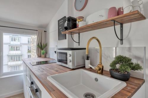 a kitchen with a sink and a microwave on a counter at Appartement Cosy proche Arc Triomphe - 2P in Paris