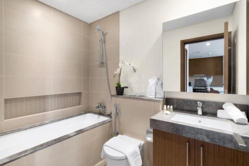 een badkamer met een bad, een toilet en een wastafel bij Silkhaus elegant 1BDR pad with Marina and Beach views new building in Dubai