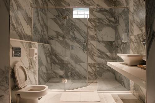 a bathroom with a shower with a toilet and a sink at La Fattoria Resort in Mombasa