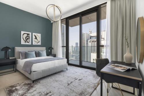 a bedroom with a bed and a desk and a large window at Silkhaus homely 2BDR with stunning Downtown view with Balcony in Dubai
