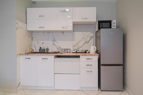 kuchnia z białymi szafkami i lodówką w obiekcie OMMPBooking w mieście Częstochowa