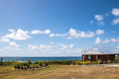 una casa en la playa con el océano en el fondo en Charmant chalet belle vue sur la mer 100% autonome, en Le Gosier