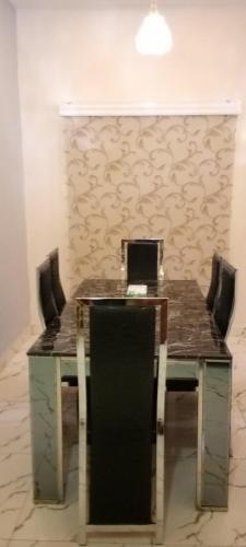 a table with chairs and a laptop on top of it at 778 Stone House Apartment in Gwarinpa