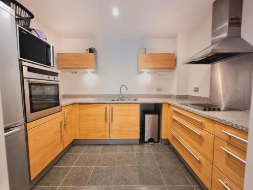 uma cozinha com armários de madeira e electrodomésticos de aço inoxidável em Riverview Apartment em Cardiff
