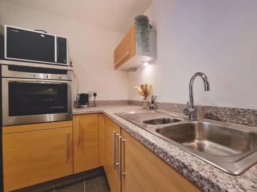 cocina con fregadero y microondas en Riverview Apartment en Cardiff