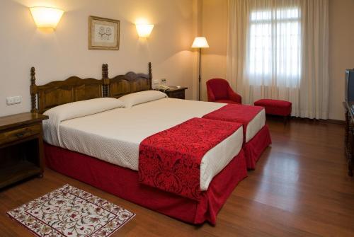 a bedroom with a large bed with a red blanket at Hotel Pazo O Rial in Vilagarcia de Arousa