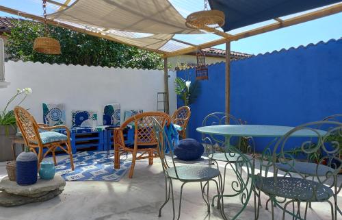 un patio con sillas, mesas y una pared azul en La terrasse Majorelle., en Le Passage