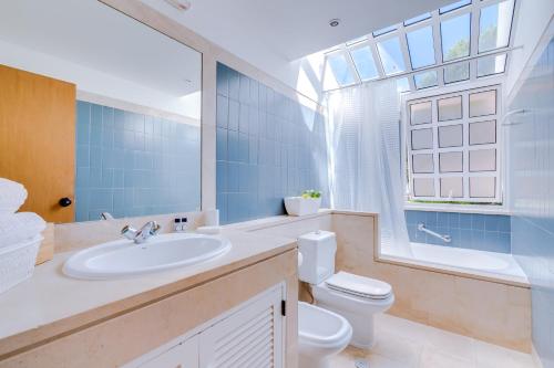 Un baño con lavabo, inodoro y ventana. en AL - Moradia Vila Brasil, en Vilamoura