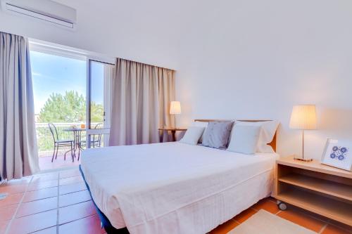 Un dormitorio con una cama grande y un balcón. en AL - Moradia Vila Brasil, en Vilamoura