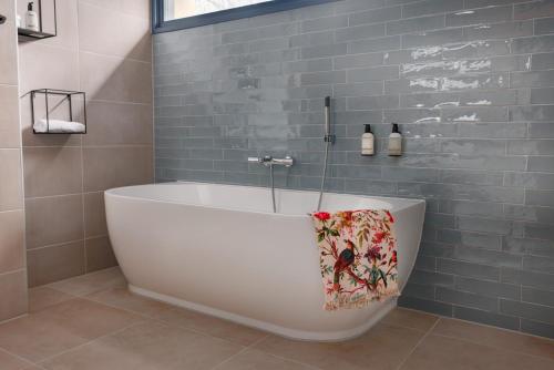 a bath tub in a bathroom with blue tiles at Buitenplaats Iepenoord in Oostkapelle