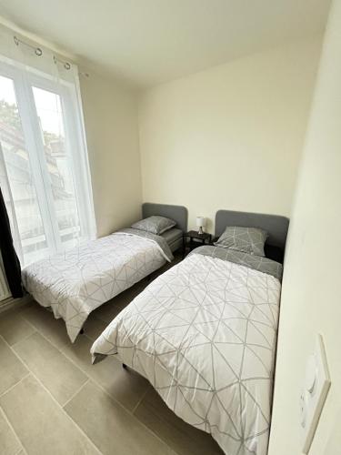 2 bedden in een slaapkamer met een raam bij Sublime Appt refait à neuf ! in Argenteuil