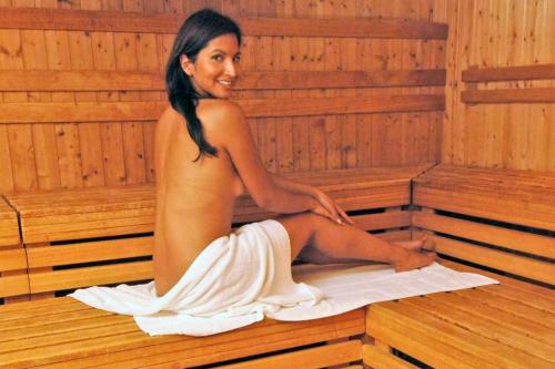 a woman is sitting in a sauna at Hotel Agostini in Bellaria-Igea Marina