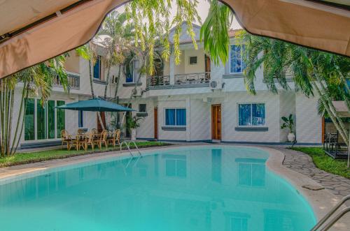 a swimming pool in front of a house with an umbrella at La Fattoria Resort in Mombasa