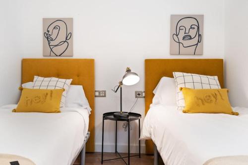 2 camas con almohadas amarillas en un dormitorio en Enamorats, en Barcelona