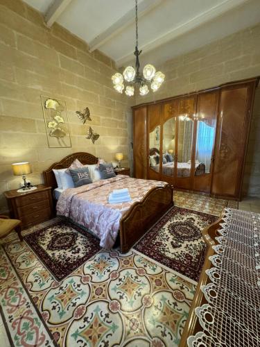 a bedroom with a large bed and a chandelier at B&S Accommodation 1940 House of Character Żejtun, Malta in Żejtun