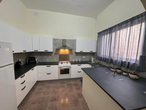 a kitchen with white cabinets and a black counter top at B&S Accommodation 1940 House of Character Żejtun, Malta in Żejtun
