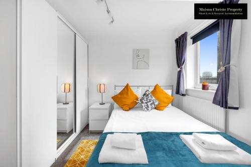 a white bedroom with a large bed with yellow pillows at Caraway Heights 2Bedroom Apt Sleeps 6 in Canary Wharf, London with Free Parking, Wifi & Leisure By Maison Christo Property Short Lets & Serviced Accommodation in London