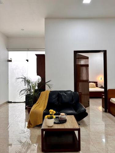 a living room with a black leather couch and a table at Teak Stays in Prayagraj