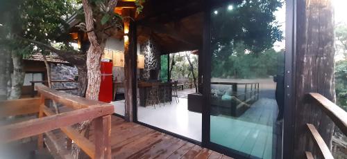une porte en verre sur une terrasse avec un arbre dans l'établissement Casa das Orquídeas, à Bonito