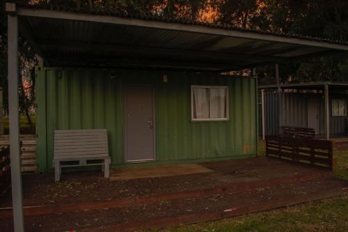 a green shed with a white chair in front of it at Cabañas El Calabres in Tacuarembó