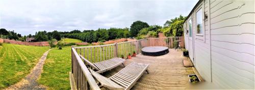 a deck with two chairs and a table on a house at Shepherd's Hut at Cefn Tilla Court in Usk
