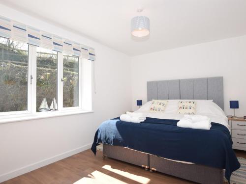 - une chambre blanche dotée d'un lit avec des draps bleus et des fenêtres dans l'établissement 2 Bed in Bideford 49224, à Bideford