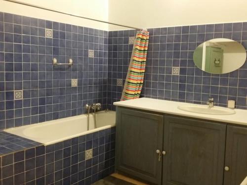 uma casa de banho em azulejos azuis com uma banheira e um lavatório em Maison dans un mas le Moulin Piot em Bellegarde