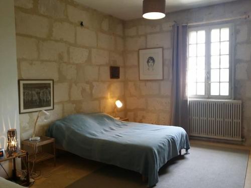 1 dormitorio con cama y pared de piedra en Maison dans un mas le Moulin Piot, en Bellegarde