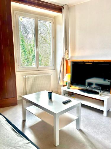 ein Wohnzimmer mit einem weißen Couchtisch und einem TV in der Unterkunft Au bord de la Furieuse, proche de la Grande Saline et des Thermes de Salins-les-Bains in Salins-les-Bains
