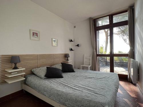une chambre avec un grand lit et une fenêtre dans l'établissement La Villa des Pins à Benat, à Bormes-les-Mimosas