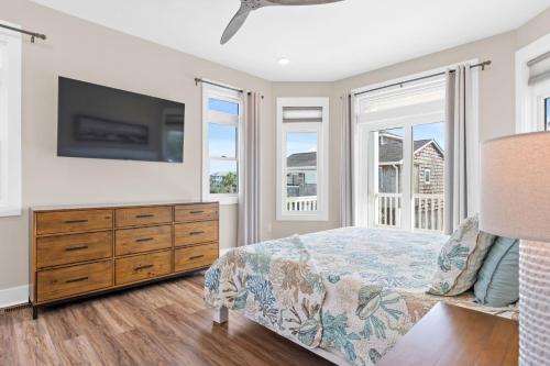 a bedroom with a bed and a tv and windows at Coastal Charm Ocean Isle Beach custom beach home with 4 bedroom, 3 bath home with pool and elevator in Ocean Isle Beach
