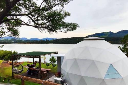 Una gran carpa blanca con una mesa y un lago. en Lunar HOME (Casa Bolha) Pé na água, en Joanópolis