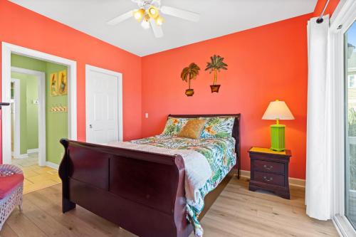 a bedroom with orange walls and a bed and a nightstand at Cherry Bomb Private heated Pool, Elevator in Ocean Isle Beach