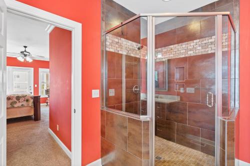 a glass shower in a bathroom with orange walls at Cherry Bomb Private heated Pool, Elevator in Ocean Isle Beach