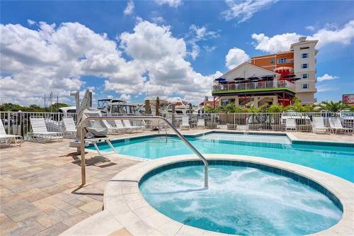 una piscina en un complejo con sillas y un edificio en Two Bedroom Condo With Views Of The Beach & Gulf en St Pete Beach