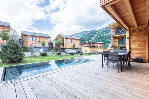 un patio con mesa y sillas en una terraza de madera en Kreischberg Pool Villas & Penthouses by ALPS RESORTS, en Sankt Lorenzen ob Murau