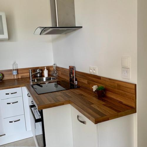 une cuisine avec des armoires blanches et un comptoir en bois dans l'établissement Lodge Calédonie, à Solliès-Pont