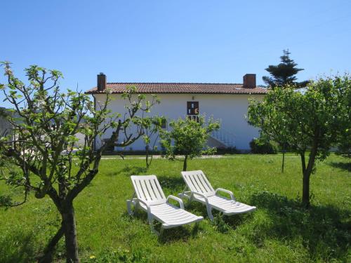 two white chairs sitting in the grass in a yard at Holiday Home Marta - ESP110 by Interhome in Esposende