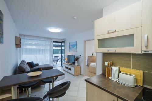 a kitchen and living room with a table and chairs at LelleMarine by BLTN Apartmanok Balatonlelle in Balatonlelle