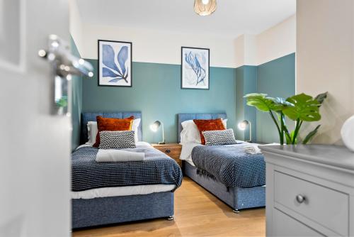 twee bedden in een kamer met blauwe muren bij 2 bedroom apartment in the Town centre with free private parking in Cirencester