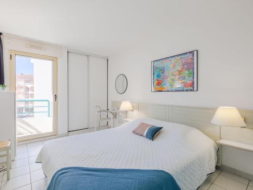 ein weißes Schlafzimmer mit einem Bett und einem Fenster in der Unterkunft Apartment L'Open-5 by Interhome in Fréjus