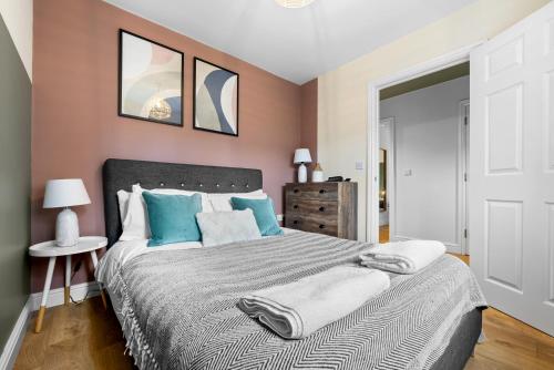 een slaapkamer met een groot bed met blauwe kussens bij 2 bedroom apartment in the Town centre with free private parking in Cirencester
