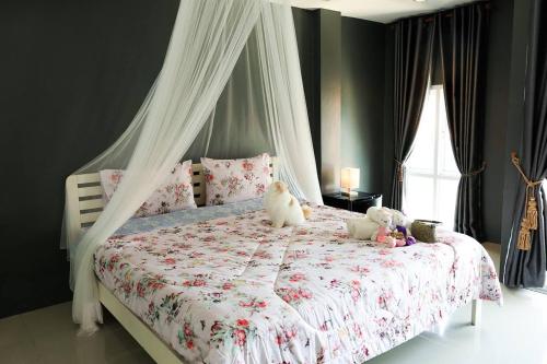dois bichos de peluche sentados numa cama num quarto em Sleep Hotel em Chon Buri
