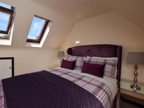 um quarto com uma cama roxa e 2 janelas em 2 Bed in Lyndhurst 75879 em Totton