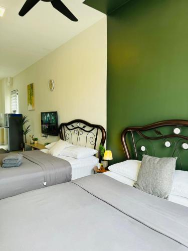two beds in a room with green walls at CoreSoho Suite by BKAstaycation KotaWarisan Sepang KLIA Airport, Free Wifi in Sepang