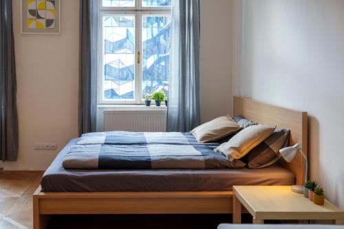 Stay Praha Apartment - New Open! في براغ: سرير في غرفة نوم مع نافذة كبيرة
