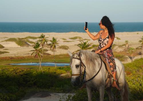 a woman is riding a horse on the beach at Pousada Por do Sol in Barra Nova